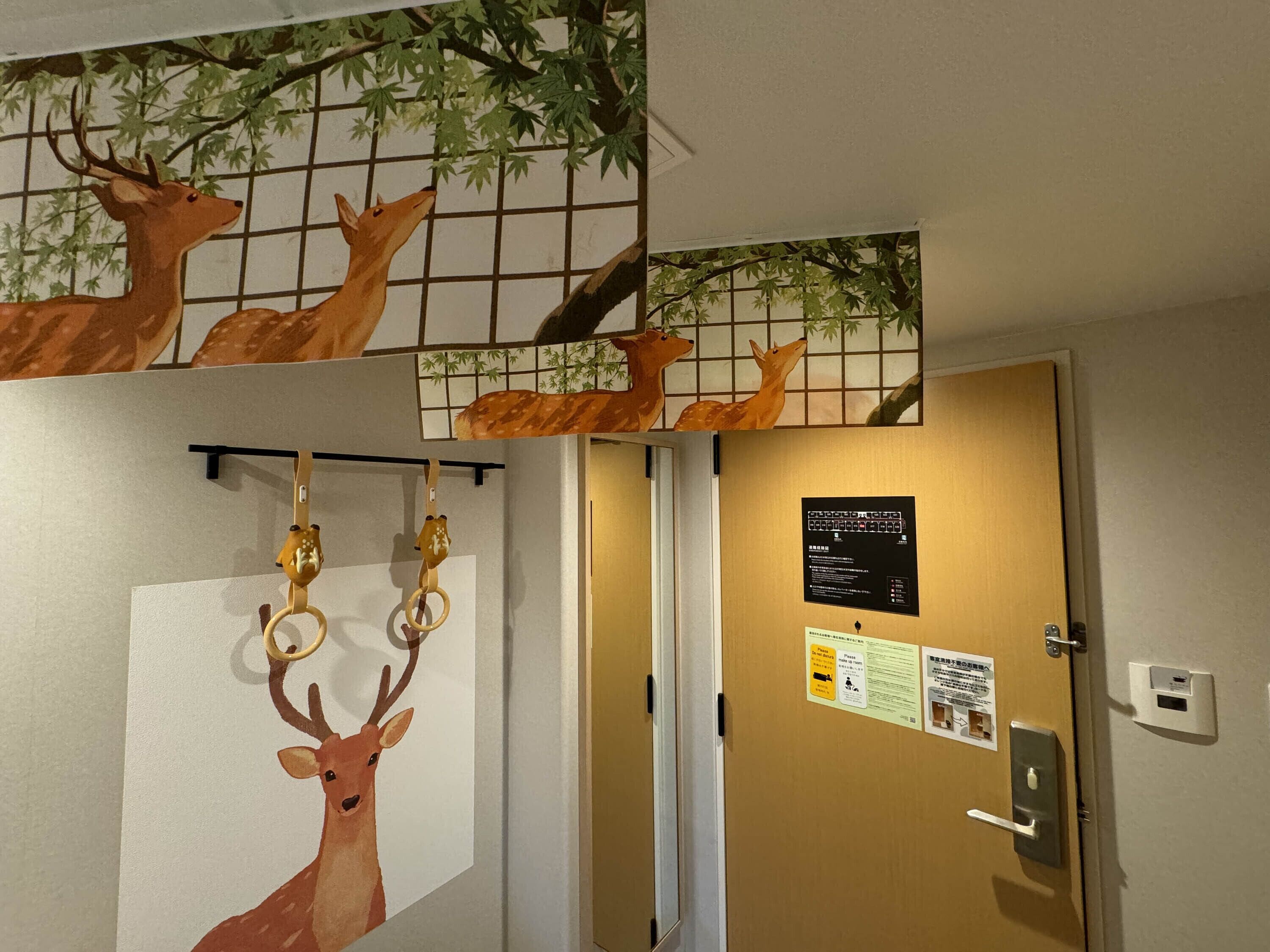 A room with a door featuring a bulletin board with notices, a wall-mounted artwork of deer, and a doorbell.