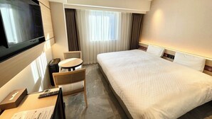 A hotel room with a large bed, a desk with a chair, a TV mounted on the wall, and a window with curtains. - Henn na Hotel Premier Nara (Nara)