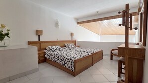 A bedroom with a wooden bed, two bedside tables, a small desk, a chair, a window with a wooden blind, and a ceiling fan. - Albufeira, 5 minutes to the beach (42) (Albufeira)