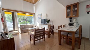 A cozy living area with a sofa, dining table, and chairs, a TV, and a kitchen area with a microwave and coffee maker. - Albufeira, 5 minutes to the beach (42) (Albufeira)
