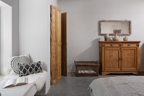 A bedroom with a wooden wardrobe, a wicker basket, a bedside table with a book, and a striped bedspread. - Villa E - Stunning Villa in Istria, Croatia (Umag)