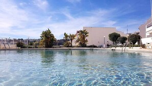 Une piscine aux eaux cristallines, avec en arrière-plan des bâtiments et des palmiers.