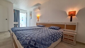 Un lit double avec une couvre-lit à motifs géométriques, une tête de lit en bois et des tiroirs de rangement de chaque côté.