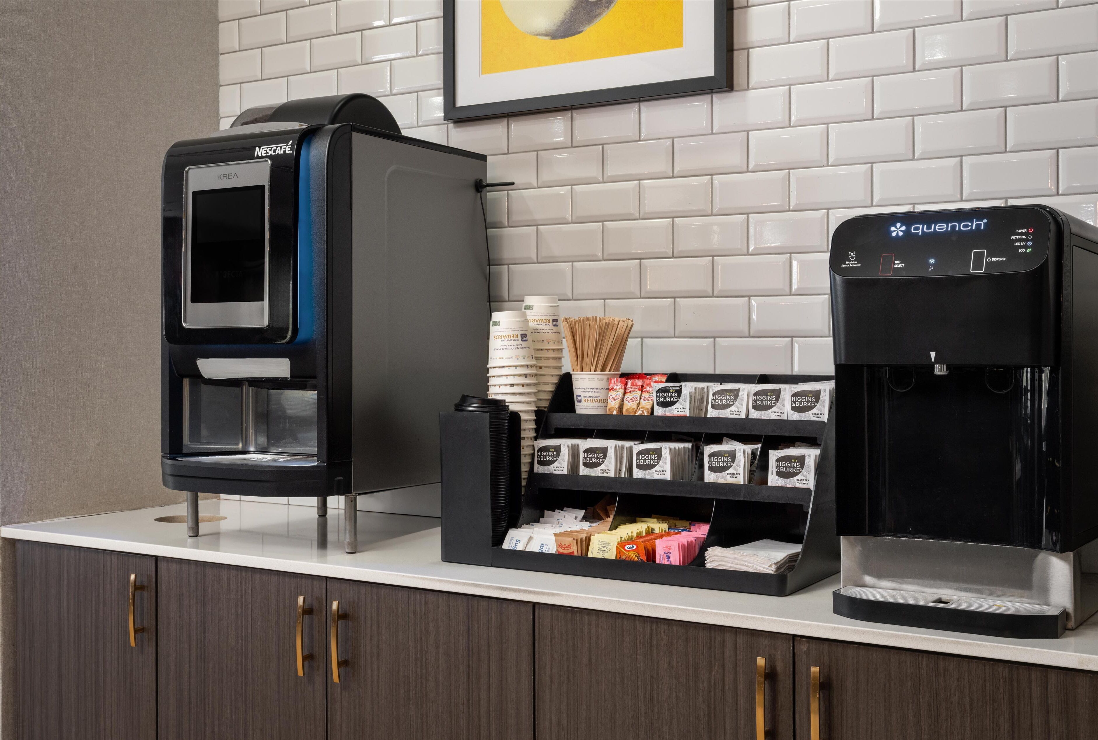 A coffee station with a Nescafé Krea machine, a quench coffee machine, and a variety of coffee pods and accessories.