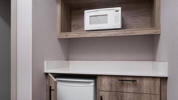 Una cocina con un microondas sobre una repisa de madera, una encimera blanca y un lavavajillas.