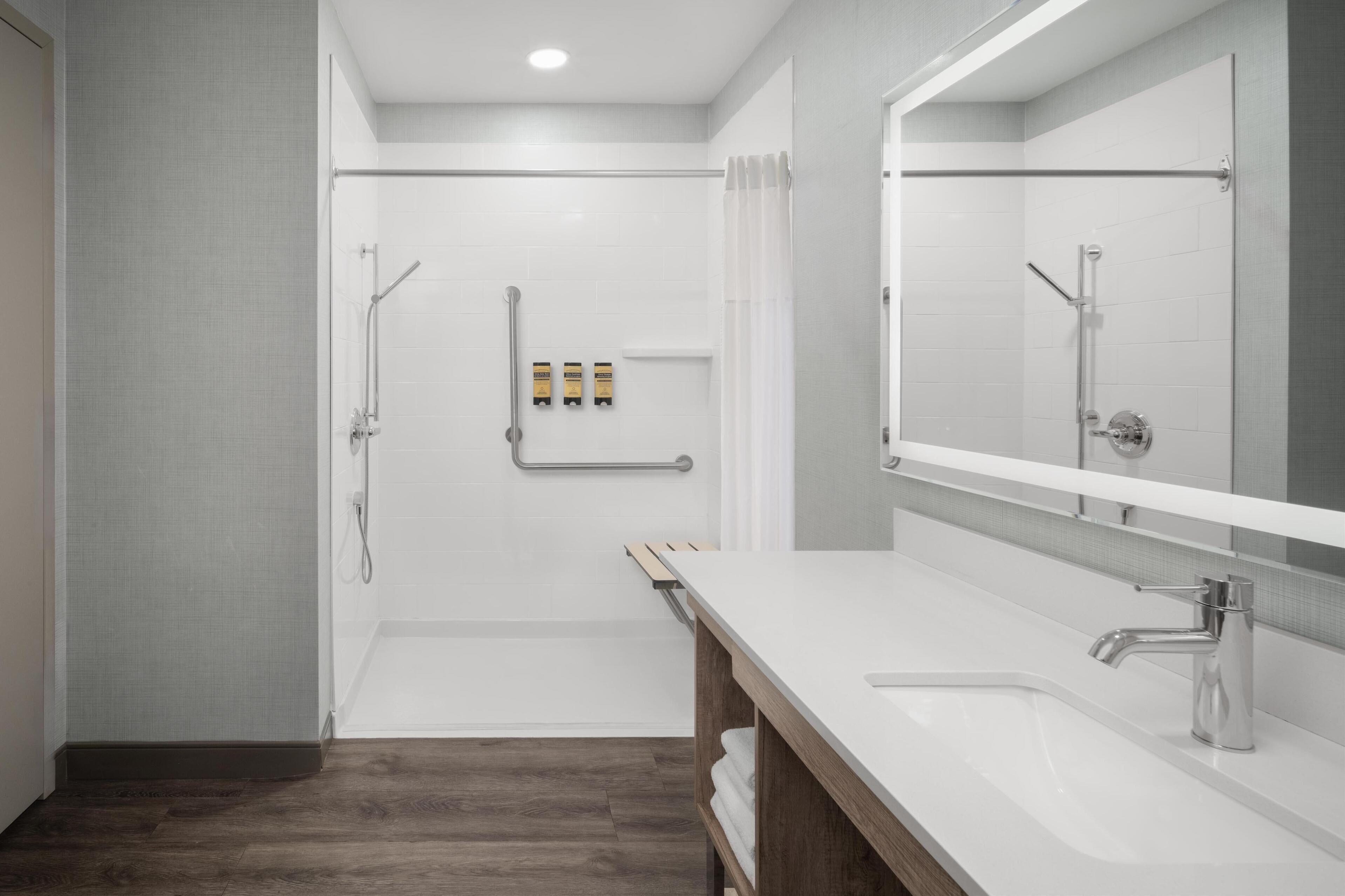 Un baño moderno con cabina de ducha, un espejo grande y un mueble de tocador de madera.