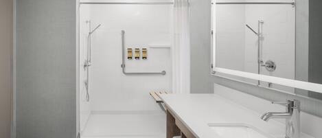 Un baño moderno con cabina de ducha, un espejo grande y un mueble de tocador de madera.