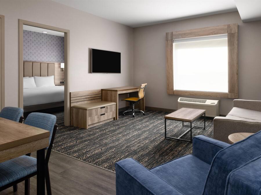 Una habitación de hotel con cama, escritorio, sillón, televisión y ventana.