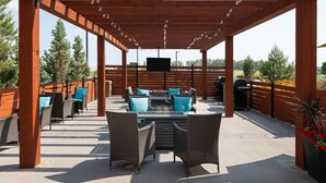 An outdoor patio with wicker furniture, a flat-screen TV, and a grill. - Best Western Premier Executive Residency Medicine Hat (Medicine Hat)