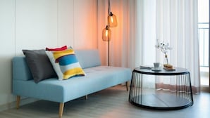 Una sala de estar moderna con un sofá azul claro, una mesa de centro negra redonda y una lámpara de pie con dos bombillas.