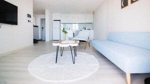 Una sala de estar moderna con un sofá azul claro, un tapete redondo blanco y un televisor de pantalla plana montado en la pared.