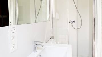 A modern bathroom with a glass shower enclosure, a white sink, and a mirror.