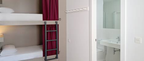 Une chambre avec un lit superposé, une échelle, une salle de bain avec un miroir et un appareil de climatisation blanc.