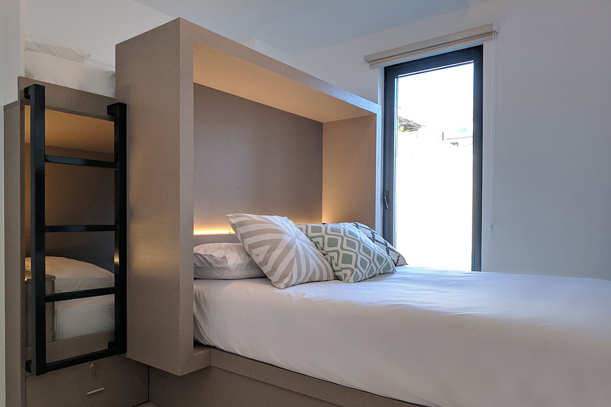 A modern bedroom with a built-in bed, a bedside table, and a window.