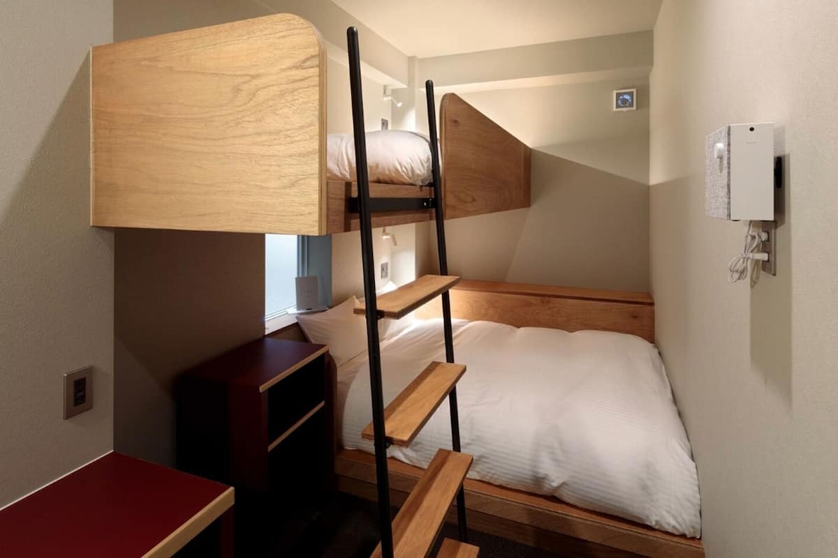 A bunk bed room with a desk and a small cabinet.