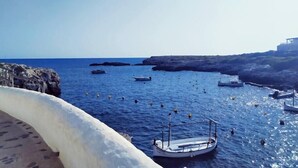 A coastal scene with boats anchored near rocky cliffs and a clear blue sky.