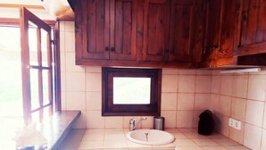 A kitchen with wooden cabinets, a window, a sink, a dishwasher, and a stove.