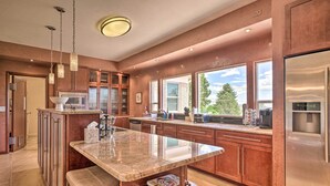 Una cocina moderna con una isla central, electrodomésticos de acero inoxidable y grandes ventanales con vistas al exterior.