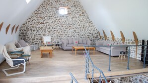 A cozy loft bedroom with a sloped ceiling, stone wall, and a wooden staircase. - Auvergne farmhouse in the heart of nature (CROS)