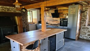 A kitchen with a wooden island, built-in appliances, and a stone wall. - Auvergne farmhouse in the heart of nature (CROS)