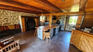 A cozy kitchen with a stone wall, wooden ceiling, and a central island. - Auvergne farmhouse in the heart of nature (CROS)