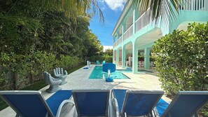 A pool area with lounge chairs, a pool table, and a building with a light blue facade. - Blue Paradise 5bed/5bath walking distance to the beach with a private pool (Marathon)