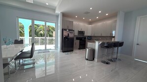 A modern kitchen with a refrigerator, microwave, and bar stools. - Blue Paradise 5bed/5bath walking distance to the beach with a private pool (Marathon)