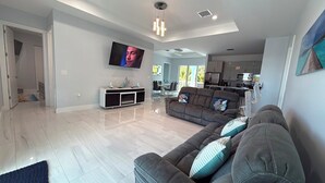 A modern living room with a flat-screen TV, a sofa with decorative pillows, a dining area, and a kitchen. - Blue Paradise 5bed/5bath walking distance to the beach with a private pool (Marathon)