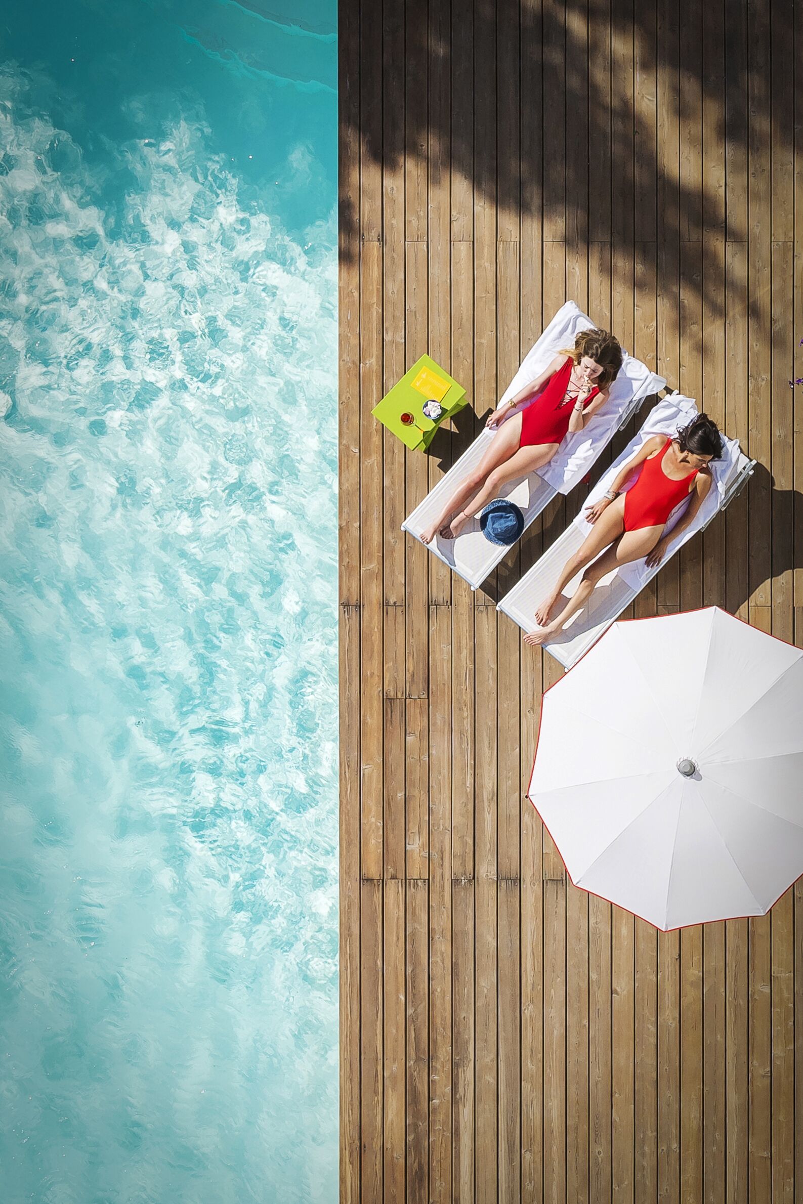A wooden deck with two sun loungers and a white umbrella.