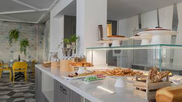 A breakfast buffet with pastries, cakes, and a variety of food items.