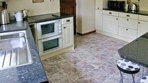 Una cocina con armarios blancos, un horno doble, un microondas y un lavamanos.
