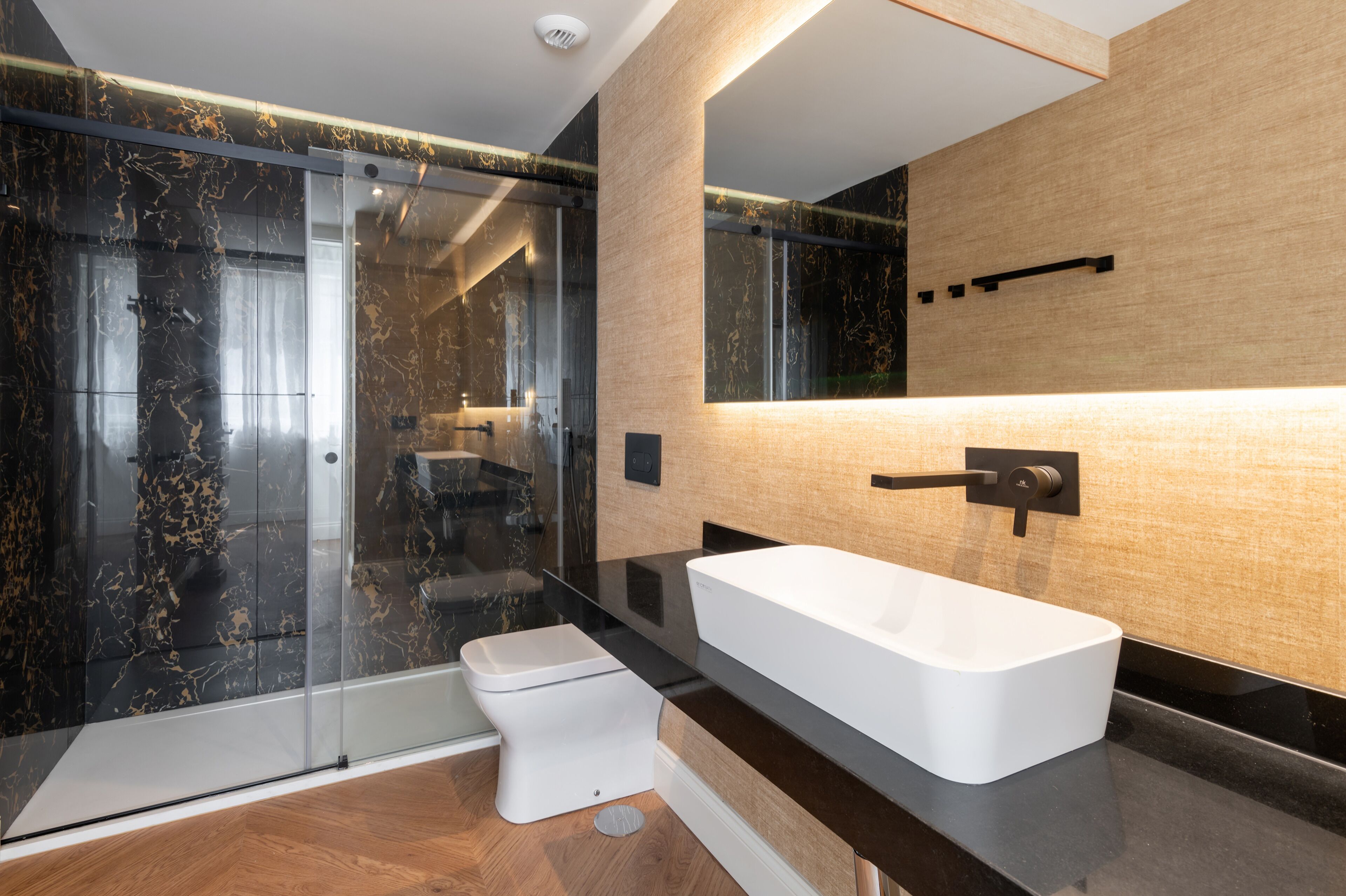 Un baño moderno con cabina de ducha de vidrio, inodoro blanco y una bañera rectangular grande.