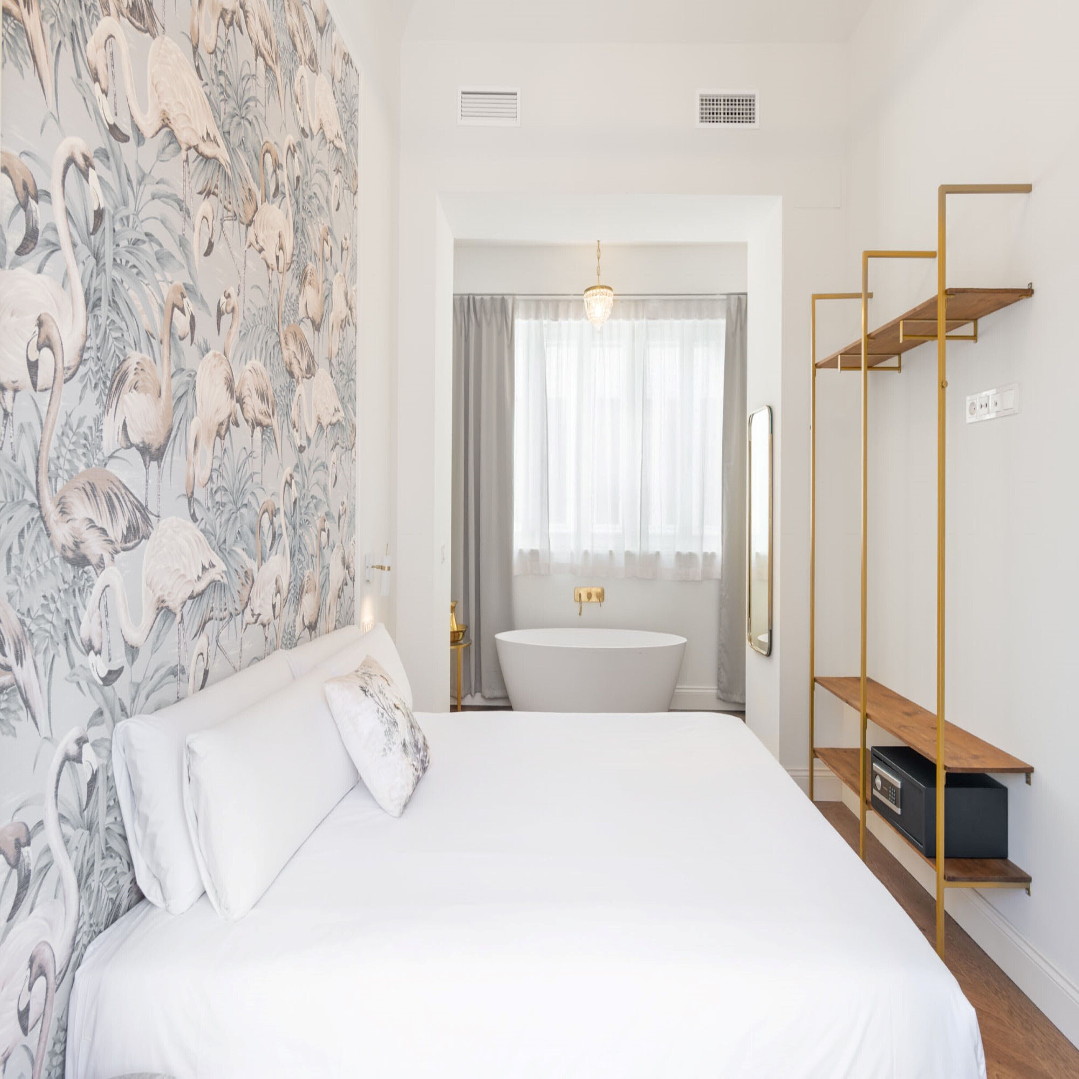 Un dormitorio con una cama grande, un baño con bañera y una pared con papel tapiz floral.