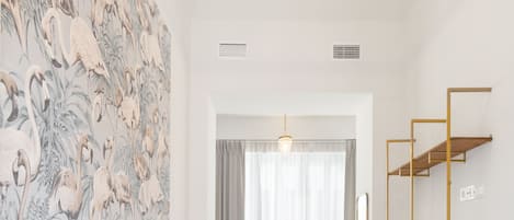 Un dormitorio con una cama grande, un baño con bañera y una pared con papel tapiz floral.