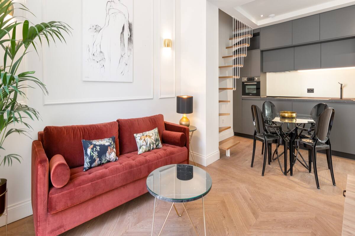 Un salon moderne avec un canapé rouge, une table basse en verre et un coin repas comprenant des chaises noires et une petite table.