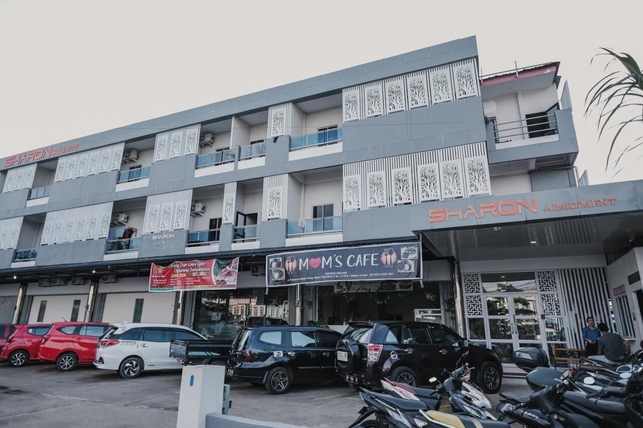 Un edifici de diverses plantes amb un cartell que anuncia "Sharon Apartments" i "Mom's Cafe" a la planta baixa.