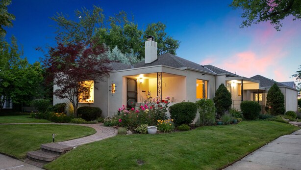 A modern two-story house with a well-maintained lawn and a variety of flowering plants.