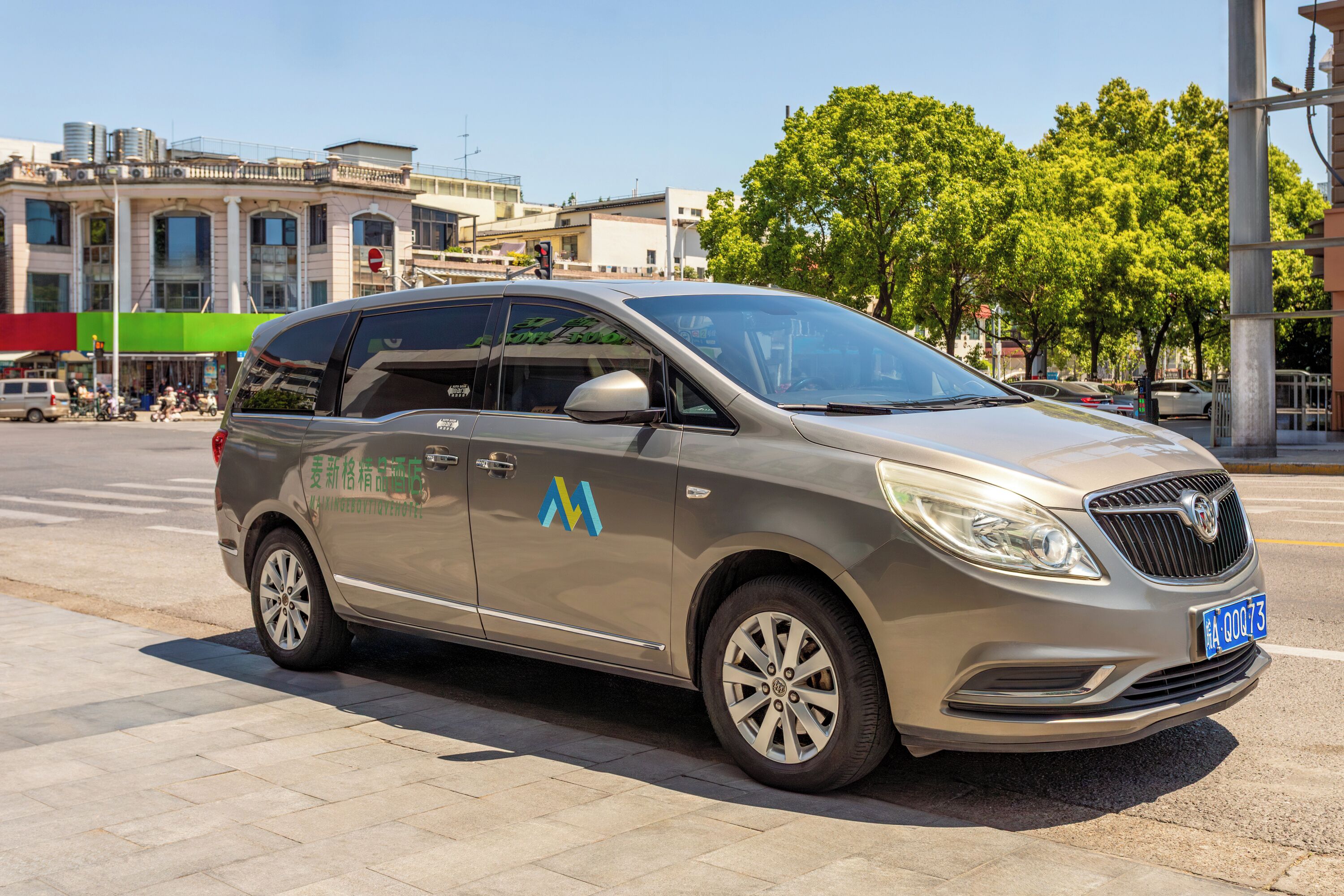 A minivan parked on a city street with a clear sky.