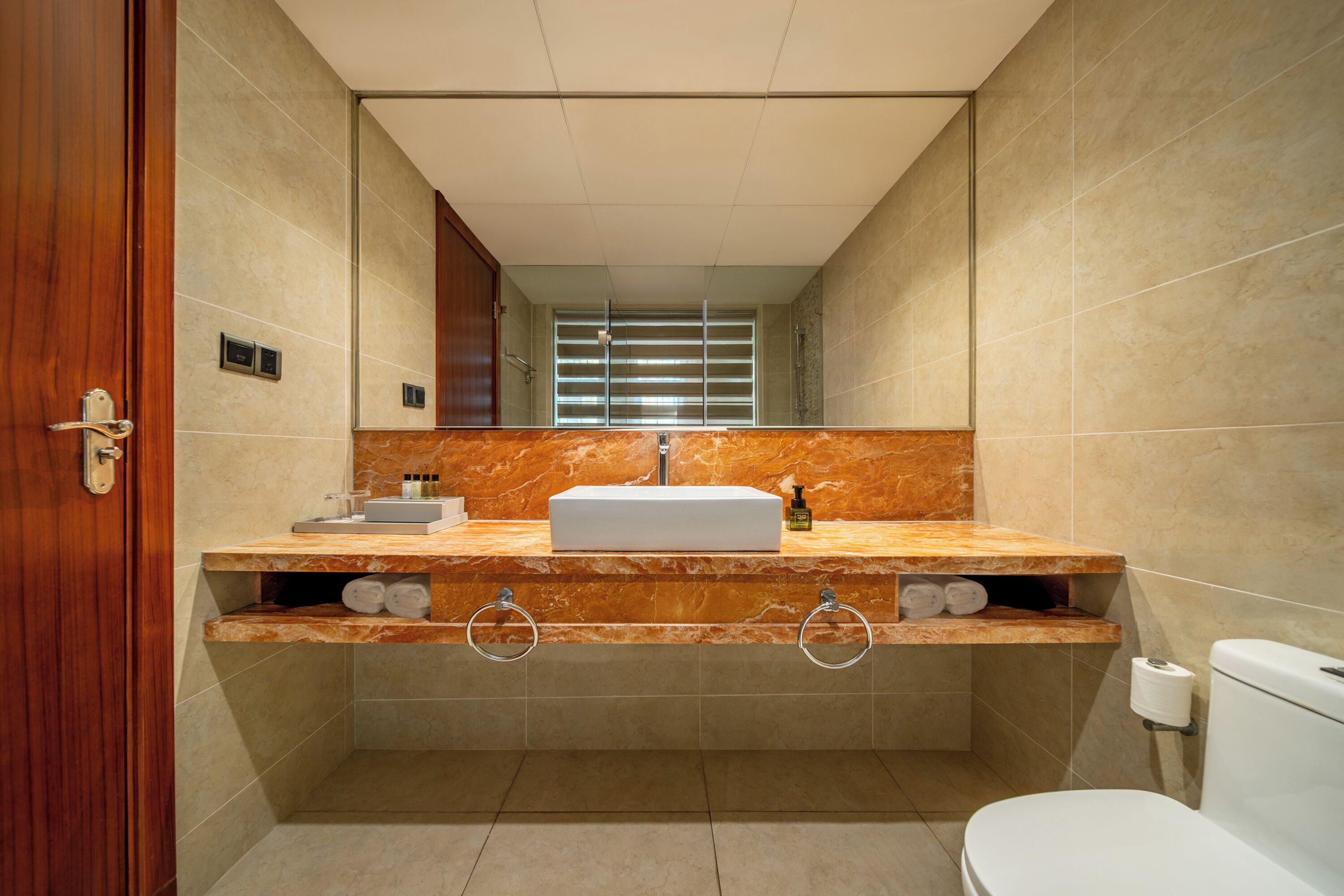 A bathroom with a marble vanity, a toilet, and a mirror.
