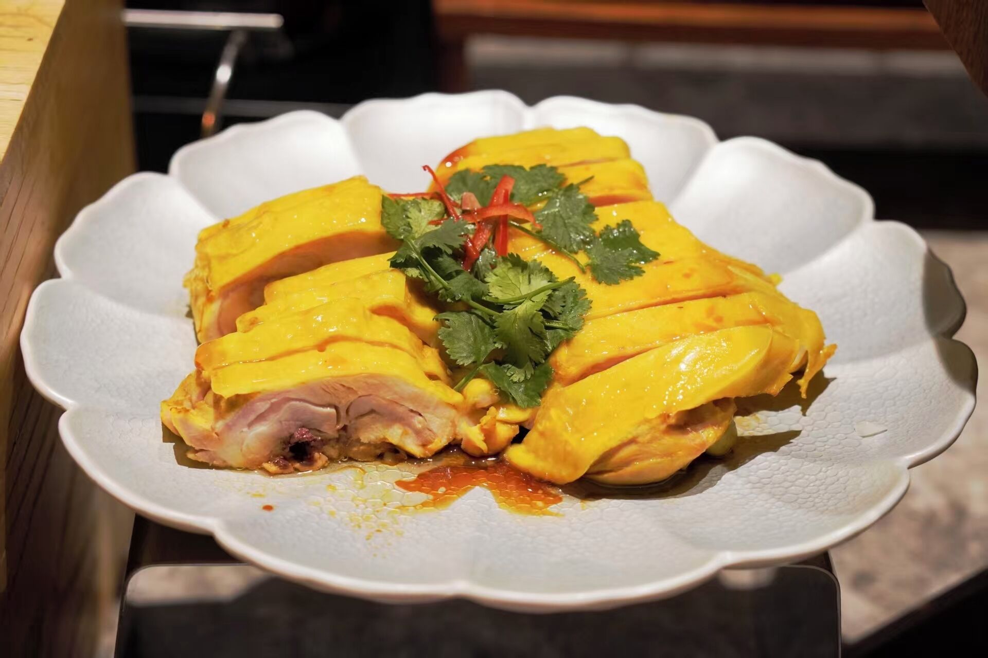 A plate of sliced chicken with a garnish of cilantro and red chili slices.