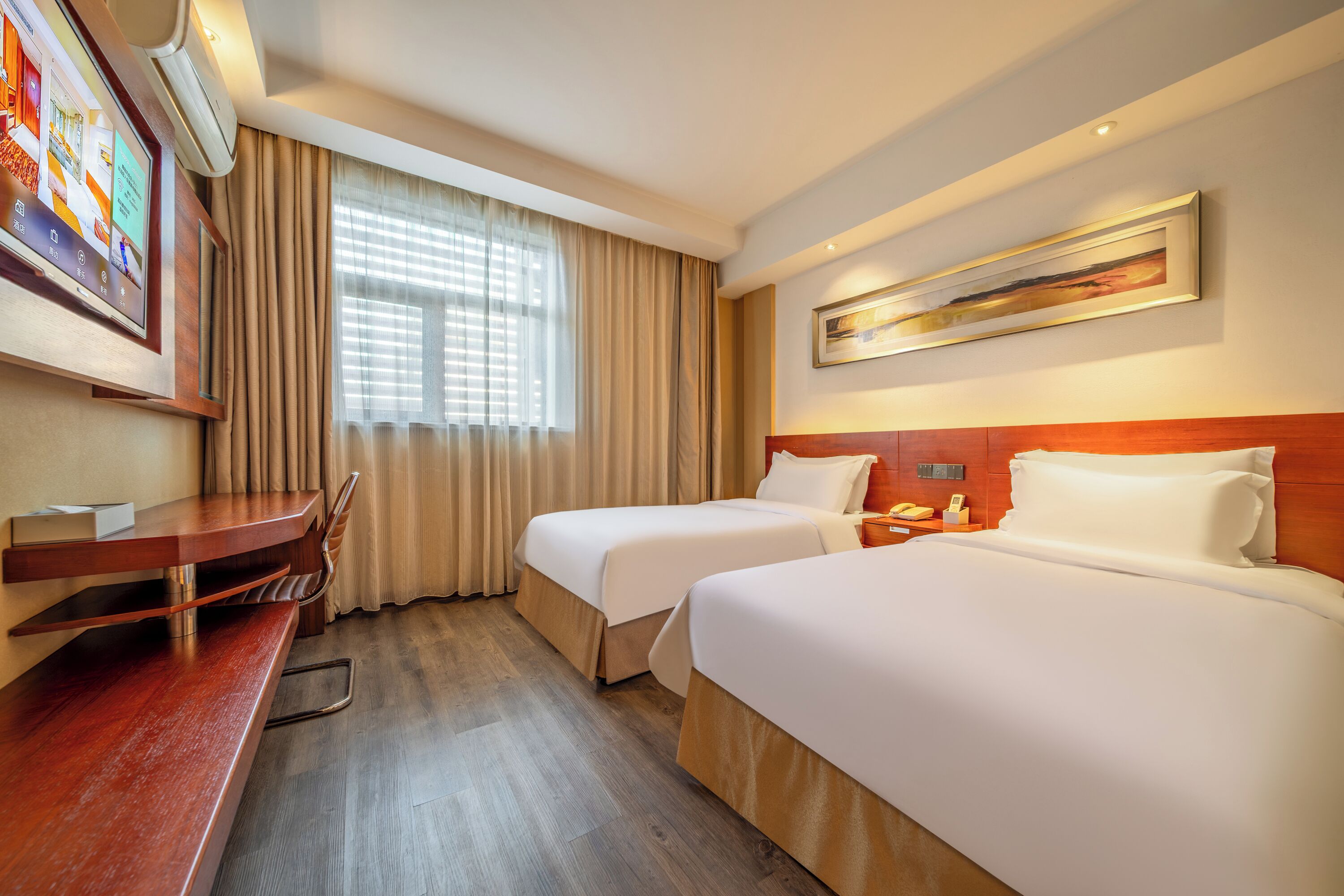 Habitación de hotel con dos camas, un escritorio, una silla, un televisor y una ventana con cortinas.