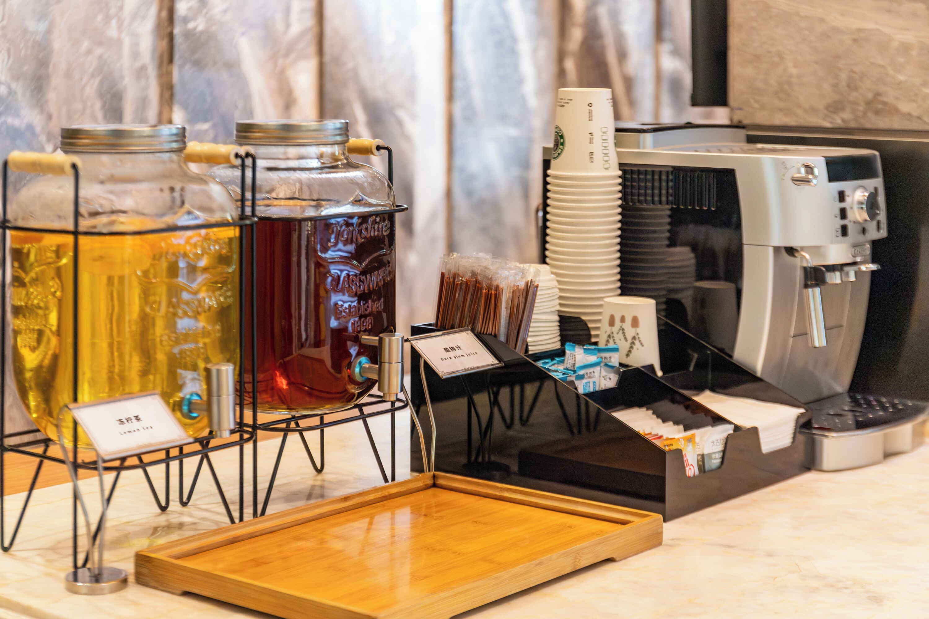Un coin café équipé d’une machine à café, d’un plateau et de deux distributeurs de boissons en verre.