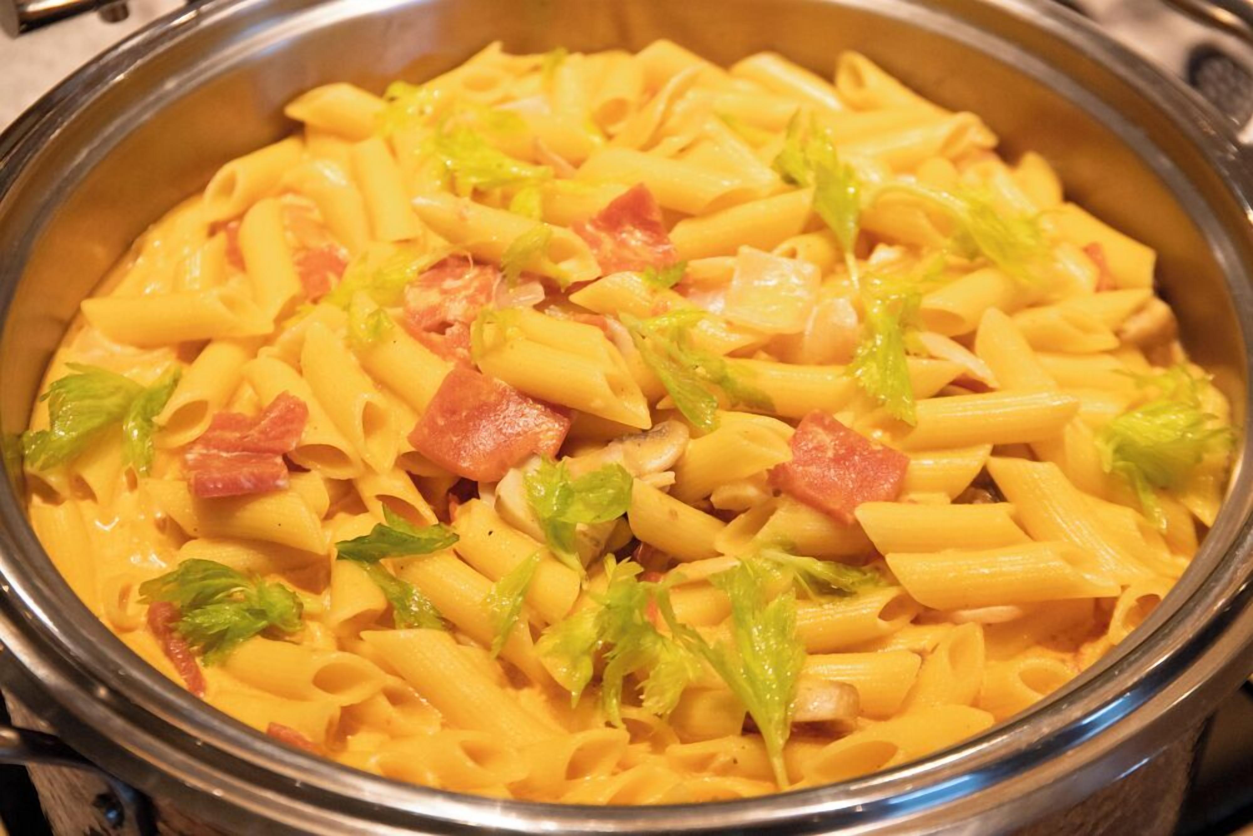 A bowl of pasta with ham and lettuce.