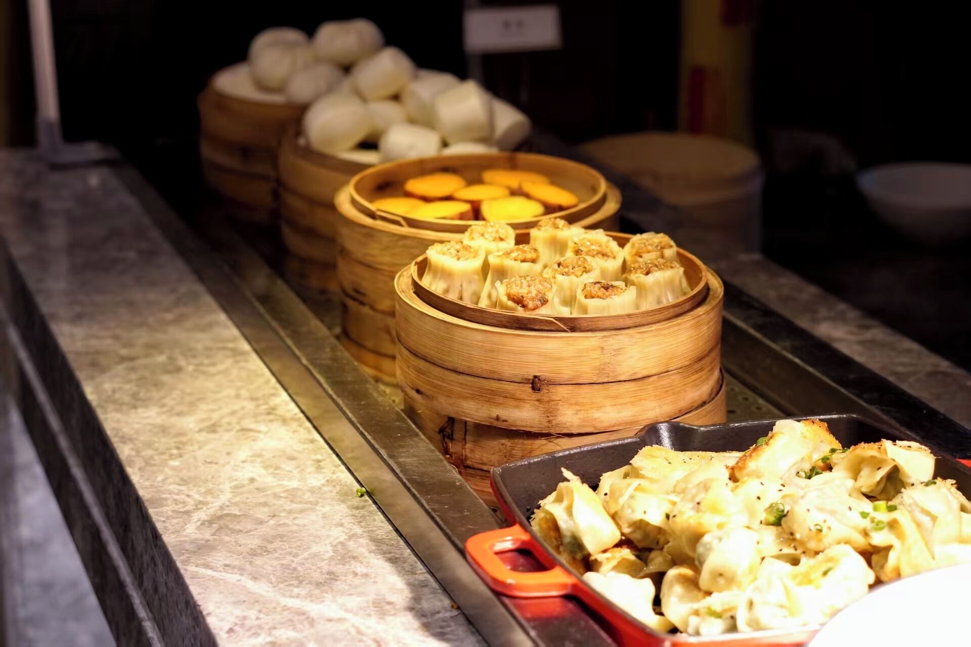 Un bufé con diversos platos, como dumplings y pasta, dispuestos en un mostrador.