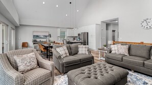 A modern living room with a grey sofa set, a matching ottoman, and a dining area with a table and chairs. - Indoor/Outdoor Pool, Pickleball, Private Hot tub (Hollister)