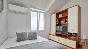 A bedroom with a bed, a TV, a wardrobe, and a window.