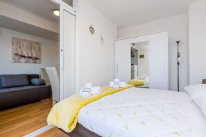 Et moderne soveværelse med en seng, en sofa og et spejl.