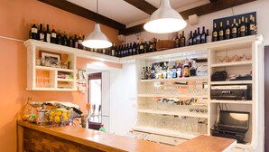 Una zona de bar con estantes llenos de botellas, vasos y una computadora portátil sobre una encimera de madera.