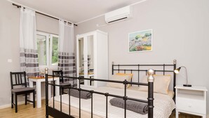 Un dormitorio con cama, mesita de noche, sillón y escritorio con silla.