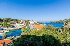 A coastal town with buildings along a waterfront, boats docked, and a clear blue sky. - Mljet Gem in Pomena!! (Pomena)